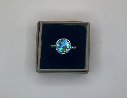 Ring with abalone shell in a black box on a light gray background
